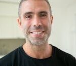 Close-up portrait of a happy man smiling indoors, exuding positivity and warmth.